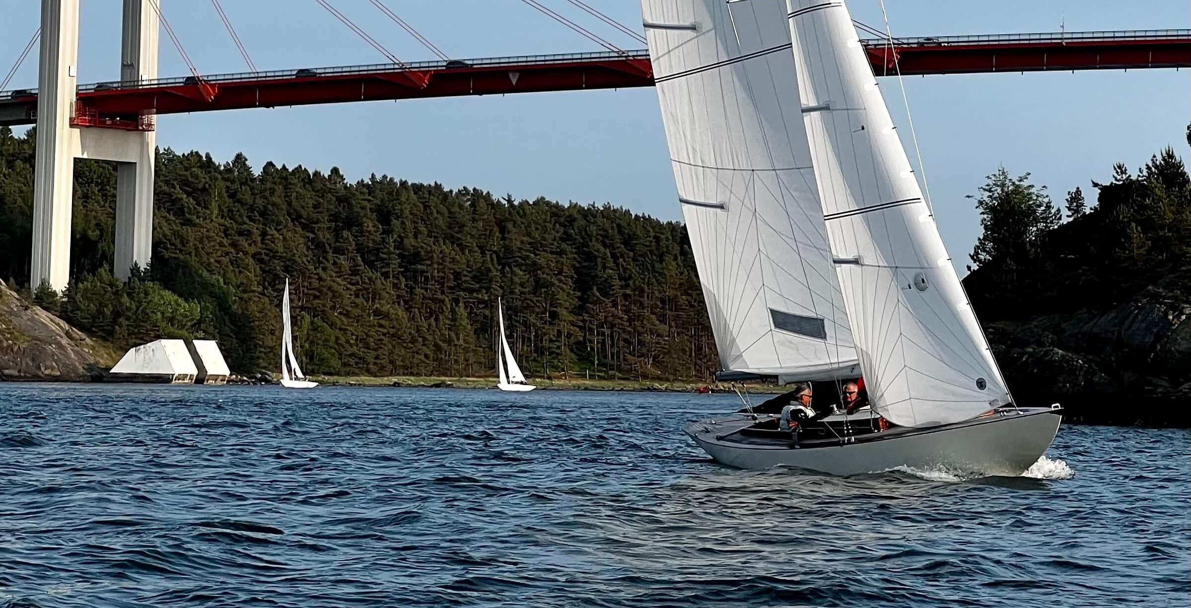 An International One Design racing under the Tjörn bridge at Almösund, with two boats astern